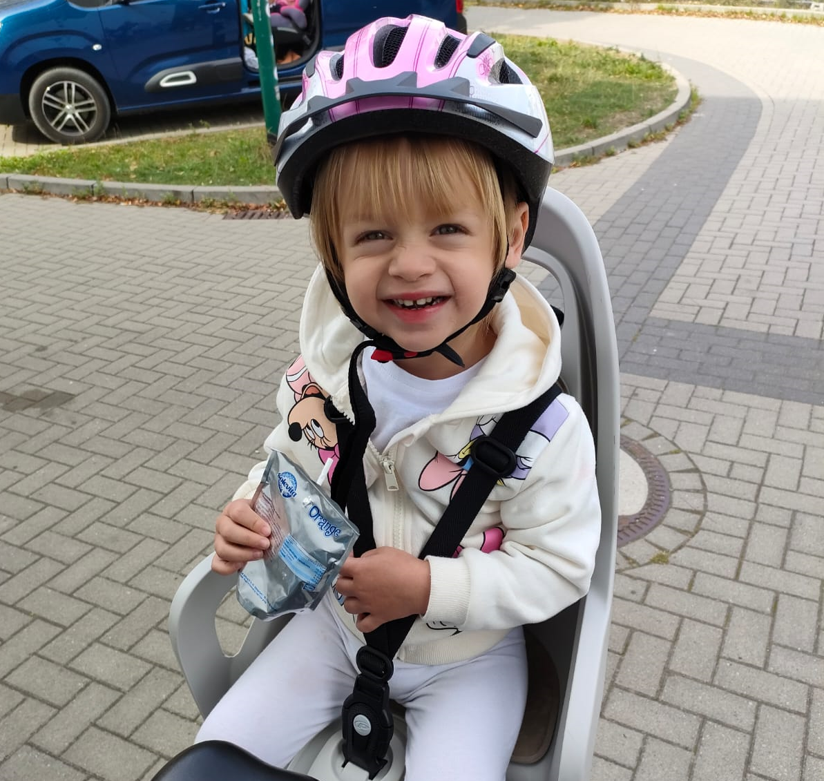 uśmiechnięte dziecko w kasku w foteliku rowerowym