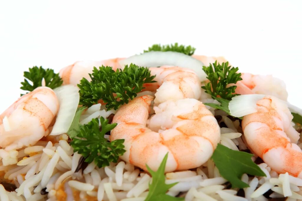 potrawa zawierająca krewetki, ryż, cebulę oraz świeże zioła